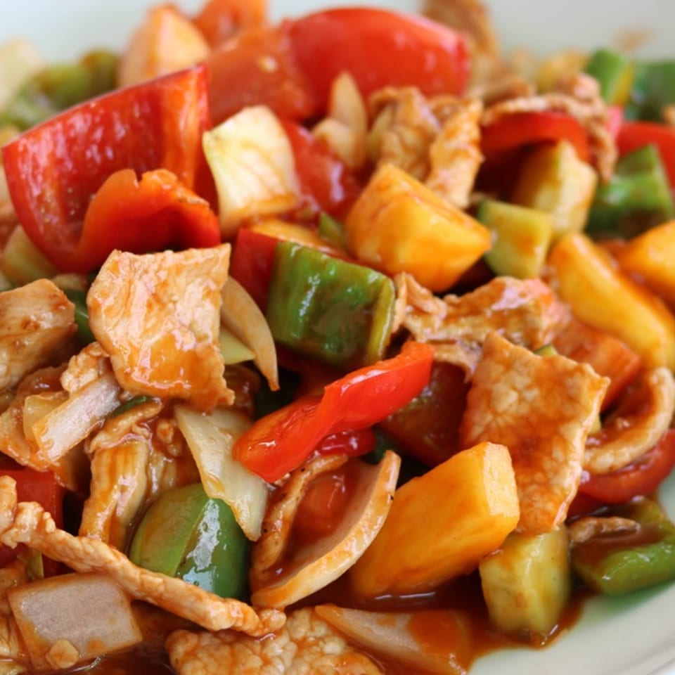 Sweet and sour pork with bell peppers, onions, and pineapple chunks in a rich sauce.